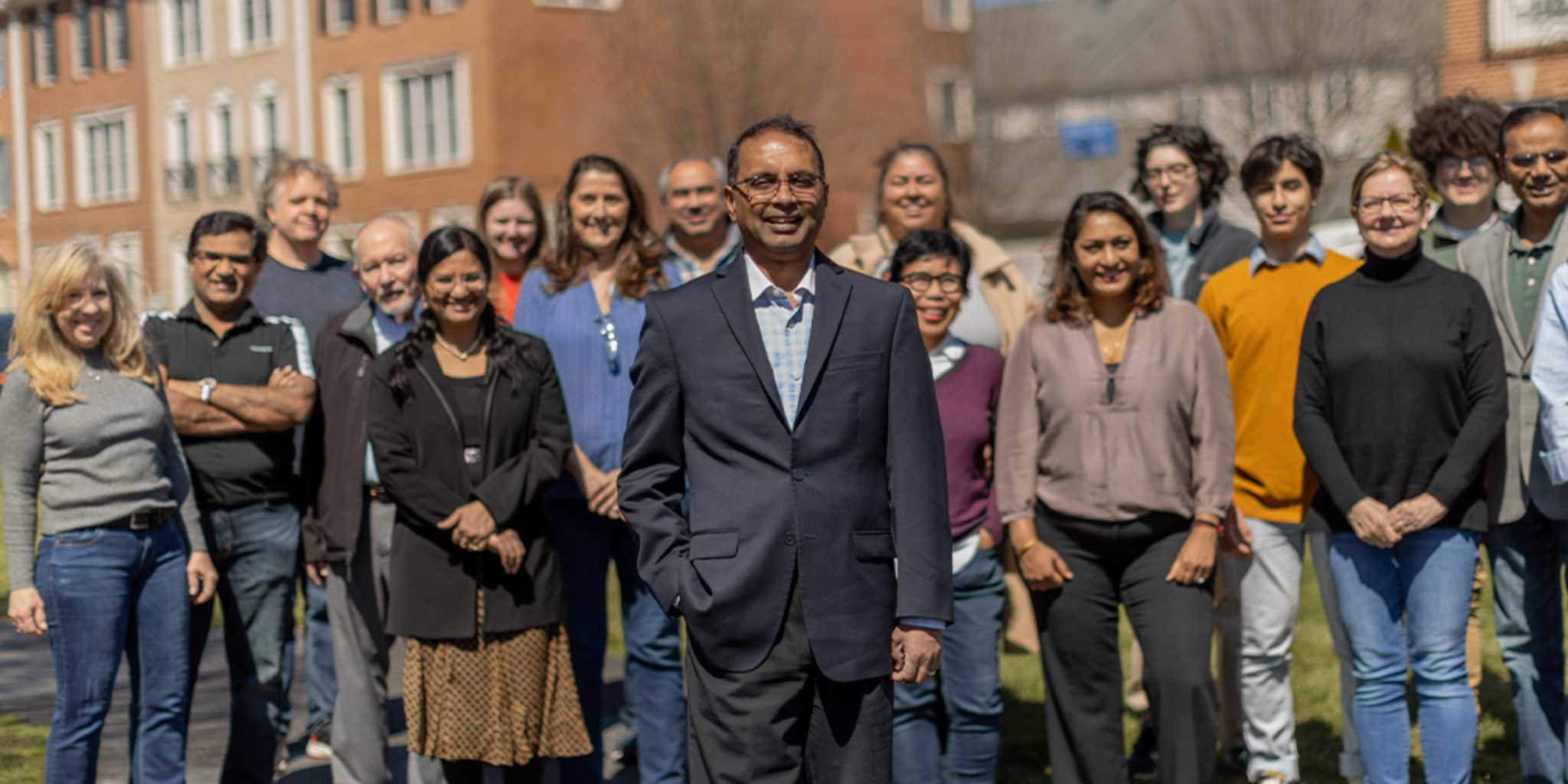 Kannan Srinivasan standing in front of a group of supporters outside